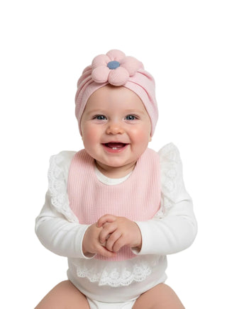 Baby wearing a pink headband and bib on a white background