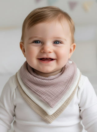 Baby wearing a pink and beige bib with a white background