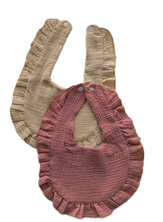 Two baby bibs, one beige and one pink, on a white background