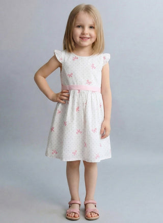Young girl wearing a white dress with pink floral patterns on a gray background