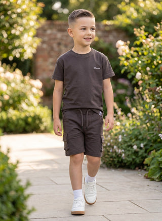 Boy wearing a beige short-sleeve T-shirt with matching cargo shorts featuring side pockets and a drawstring waist.