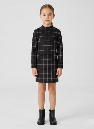 Girl wearing a black windowpane check long-sleeve shift dress with a high neck and straight silhouette.