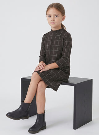 Girl wearing a black windowpane check long-sleeve shift dress with a high neck and straight silhouette.