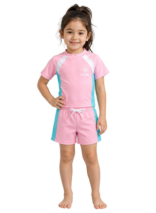 Smiling girl wearing pink short-sleeve swim top and drawstring shorts with aqua and white panels