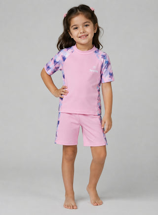 Girl wearing pink short-sleeve swim top and shorts with purple and blue geometric print panels