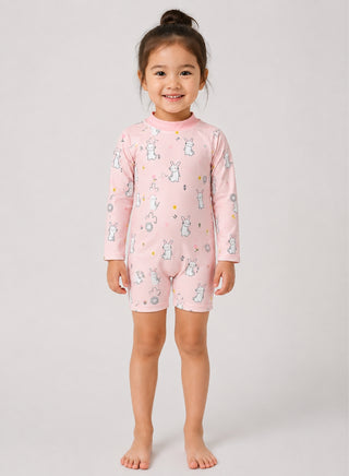 Smiling girl wearing pink long-sleeve one-piece swimsuit with white bunny and flower print