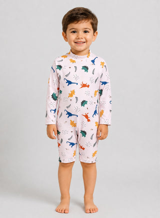 Smiling boy wearing light long-sleeve one-piece swimsuit with colorful dinosaur print