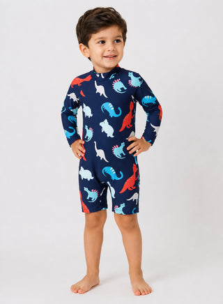 Boy wearing navy long-sleeve one-piece swimsuit with blue, red and white dinosaur print