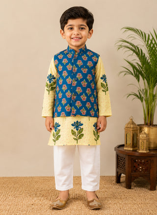 Boy wearing a cream floral printed kurta with a blue floral Nehru jacket and white pajama ethnic wear set for kids aged 1–10 years.