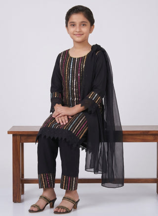 Girl wearing a black embroidered kurta with matching pants and chiffon dupatta ethnic wear set for kids aged 4–12 years.