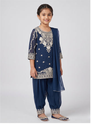 Girl wearing a blue embroidered sleeveless kurta with matching Patiala salwar, chiffon dupatta, and coordinating handbag ethnic wear set for kids aged 4–12 years.