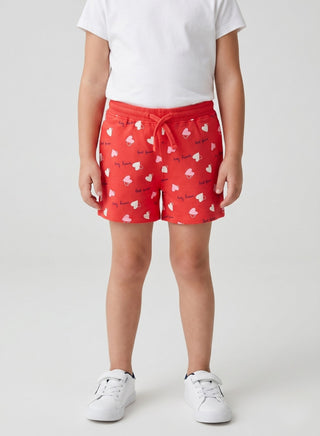 Girl wearing red heart print cotton shorts with an elastic drawstring waist for kids aged 2–8 years.
